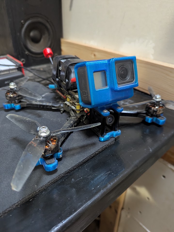A real Source One V5 FPV quad on the workbench, with a GoPro in a blue printed mount.